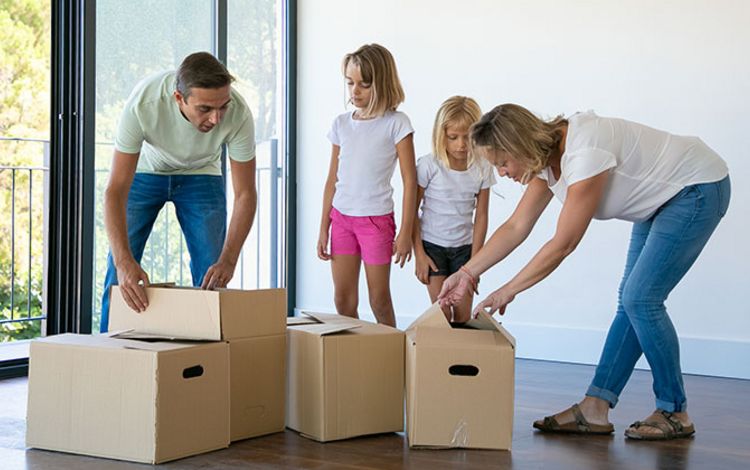 Junge Familie beim Umzug mit Kartons in neuer Wohnung