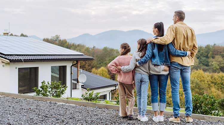 Eine Familie steht vor ihrem Haus und bestaunt die Solaranlage auf dem Dach