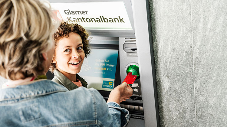 Ein Geldautomat mit zwei Personen, die Geld beziehen